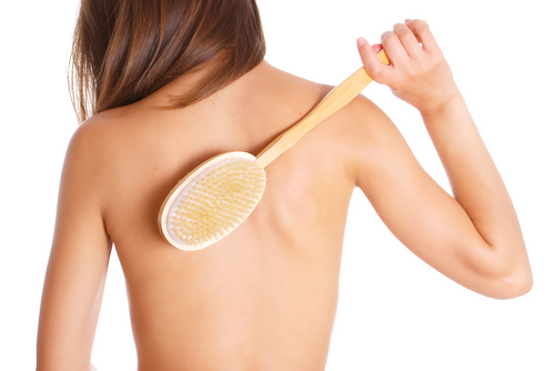 Woman dry brushing her back.